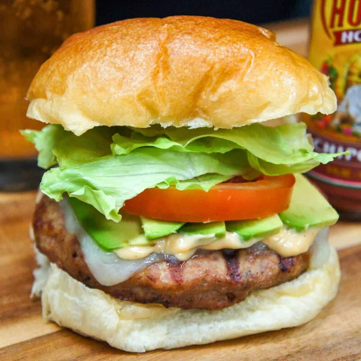 The avocado turkey burger set on a wood board.