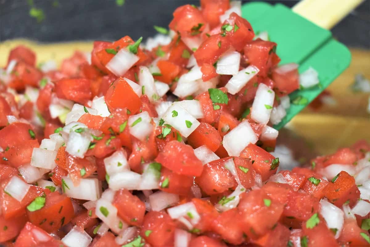 Stirring Fresh Salsa with a green rubber spatula