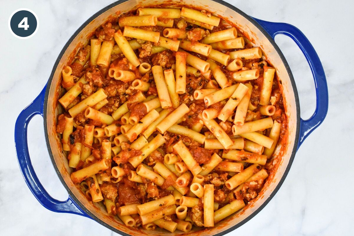 cooked ziti and sauce combined in a large blue pot.