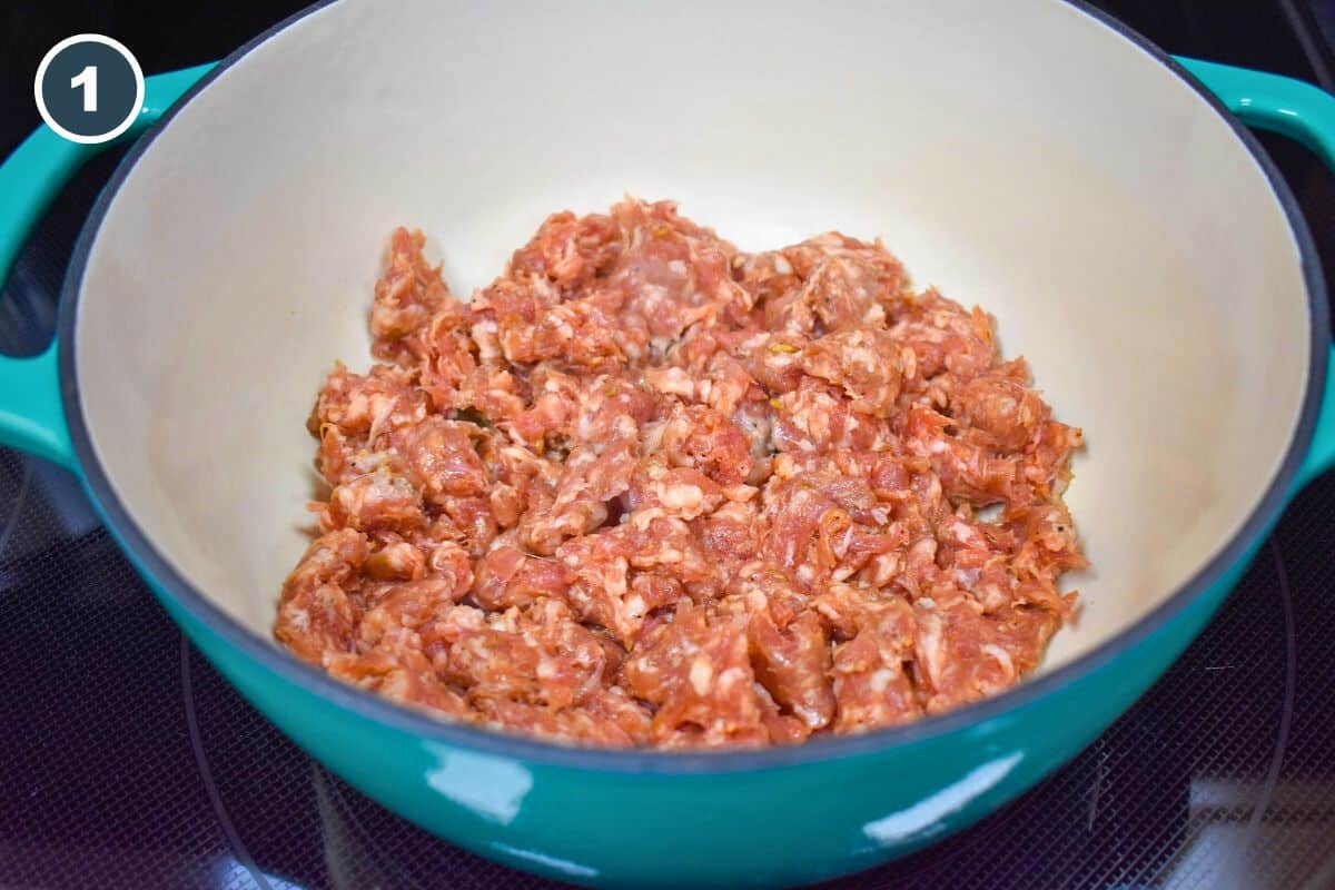 Raw sausage in a large teal pot.