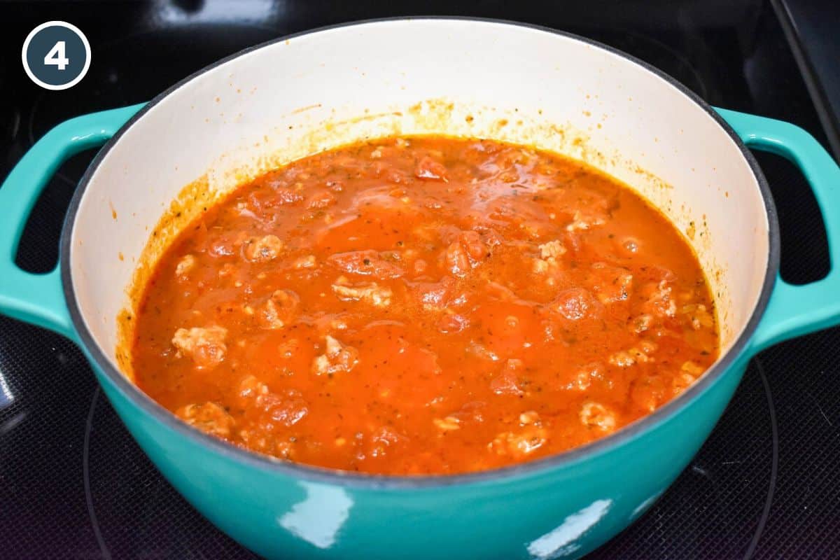 Pasta red sauce cooking in a large teal pot.