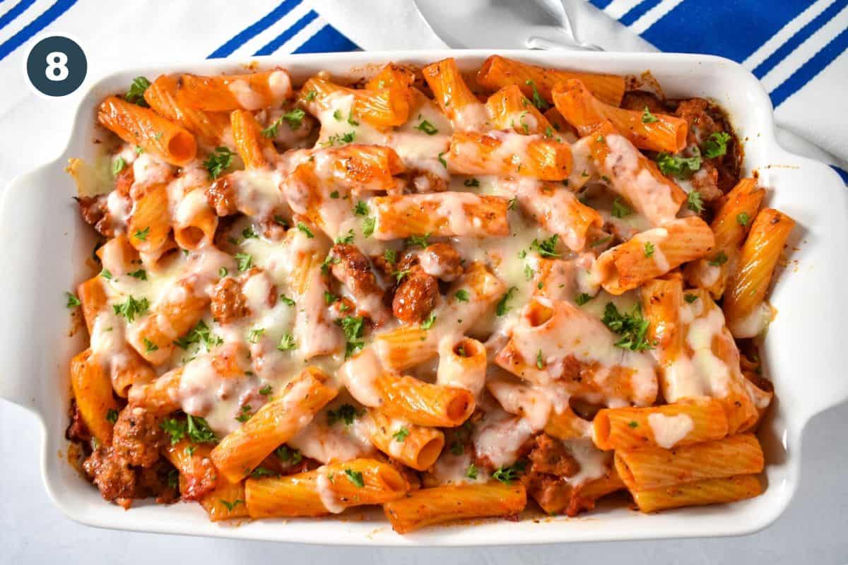 The baked pasta in a white casserole dish with a blue and white striped linen.