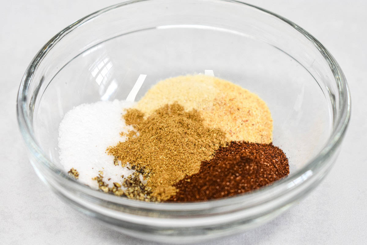Chili powder, cumin, garlic powder, onion powder, salt, and pepper in a small, glass bowl.