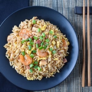 The special fried rice served on a black plate with a black linen to the left and chopsticks to the right.