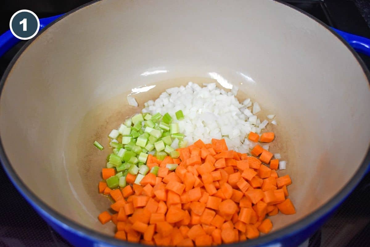 Diced onions, carrots, and celery added to a large, white and blue pot.