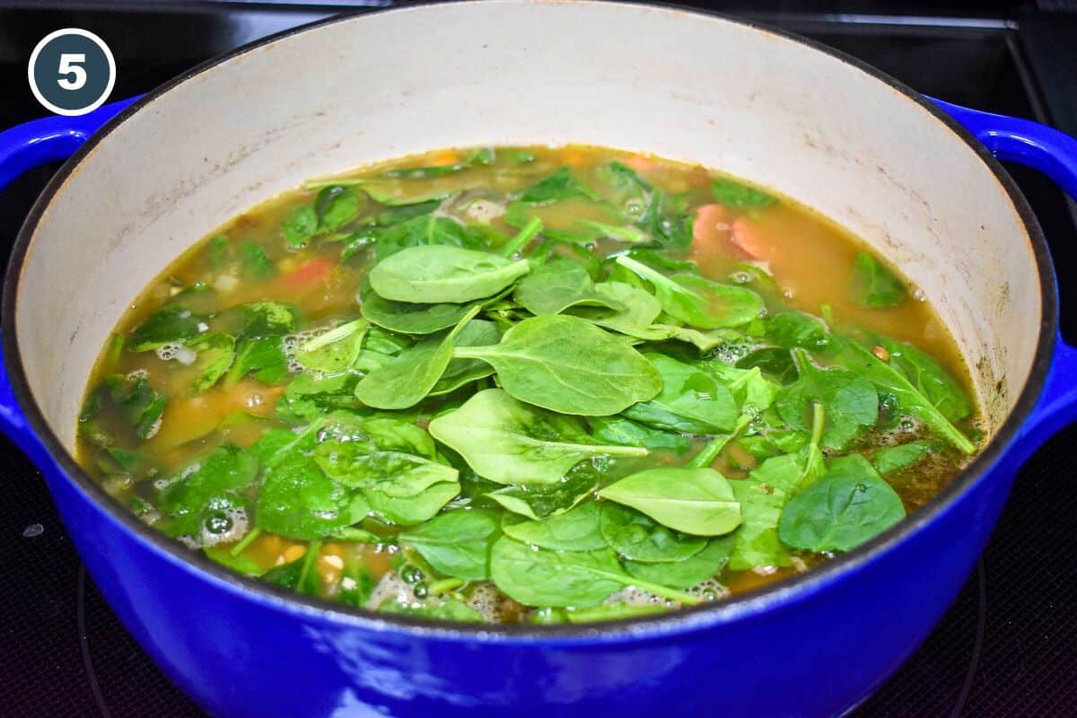 Fresh spinach added to the soup in the blue pot.