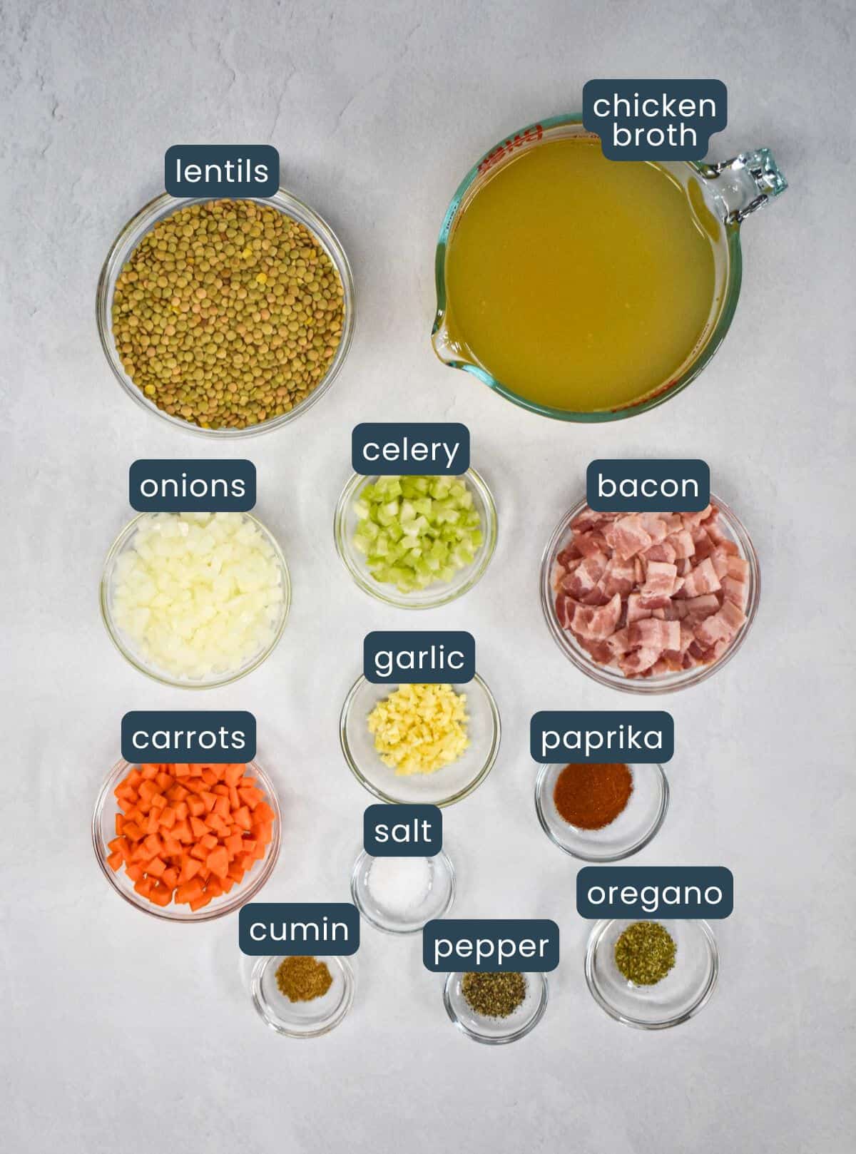 The ingredients prepped and arranged in glass bowls on a white table with each labeled with blue and white letters.