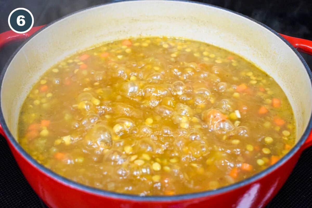 The lentil soup boiling in a large pot.