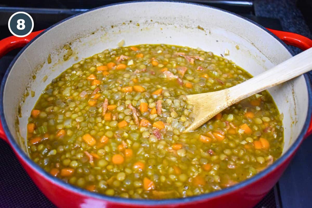 The lentil soup after cooking, still in the pot with a wooden spoon to the right.