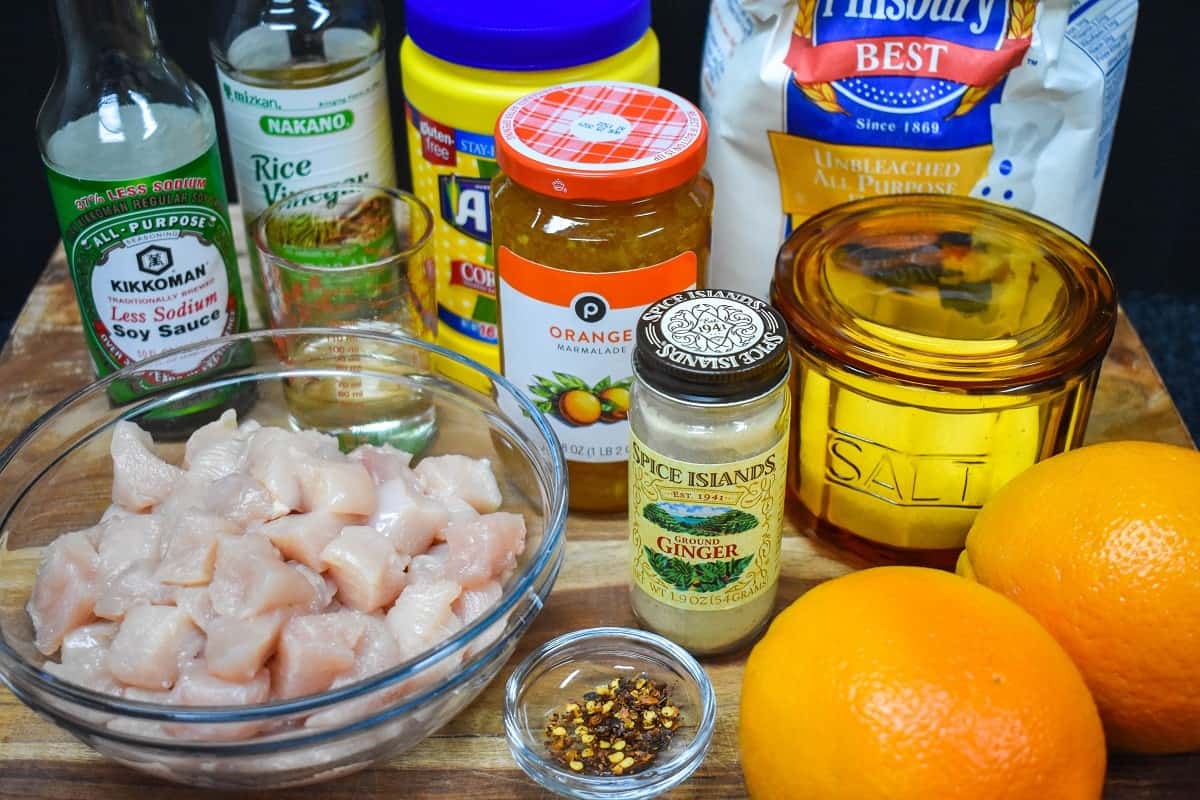 The ingredients for the orange chicken displayed on a wood cutting board.