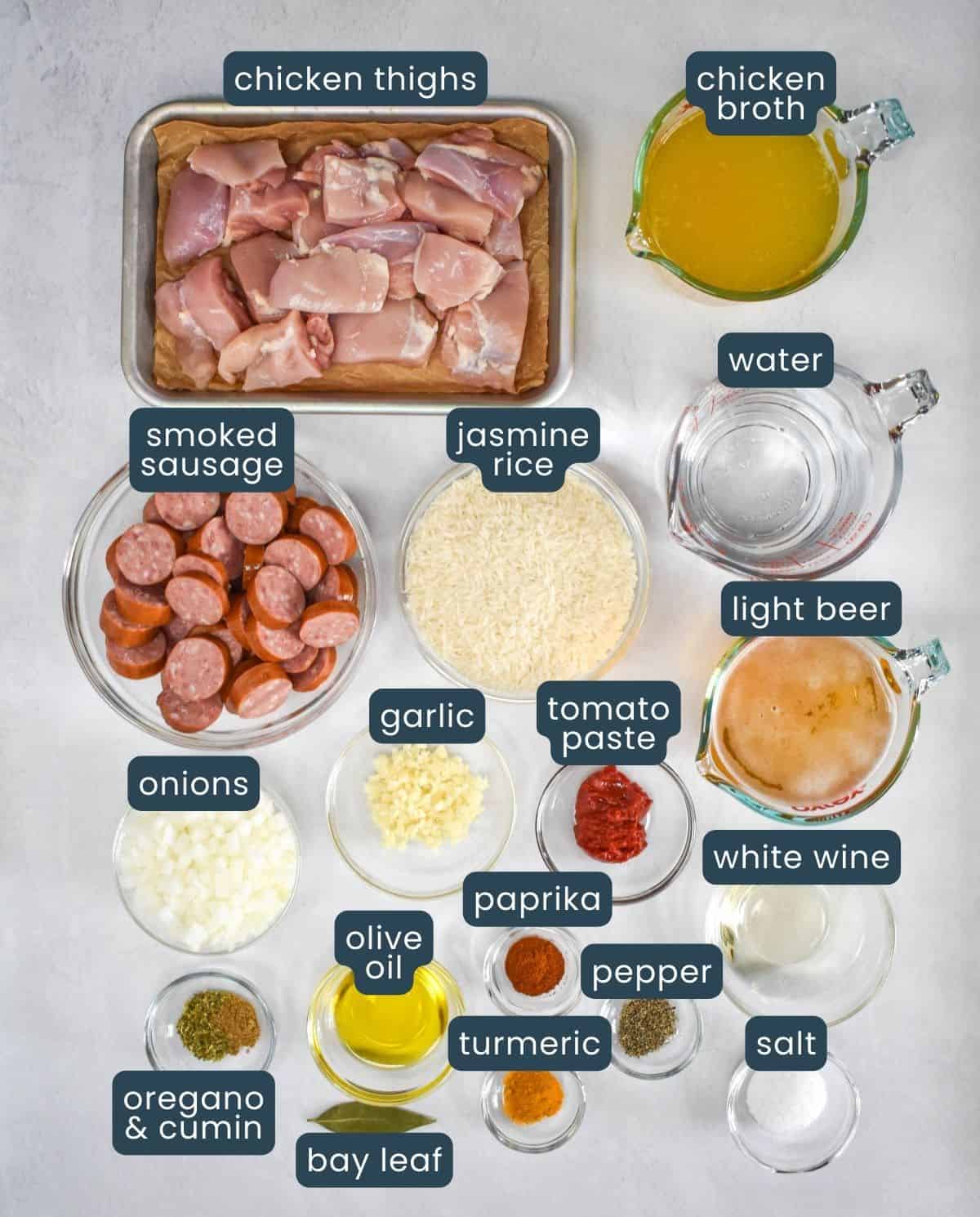 The ingredients for the rice dish prepped and arranged on a white table with each labeled with a blue graphic and white letters.