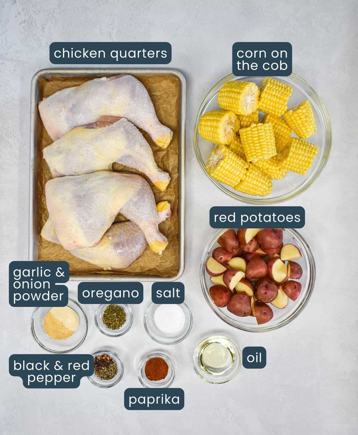 The ingredients for the chicken foil pack arranged on a white table with each labeled with blue and white letters.