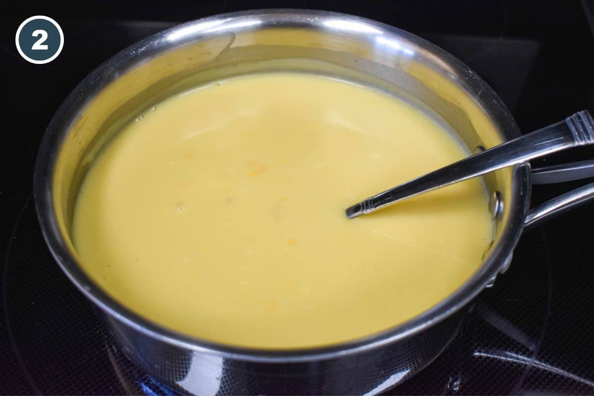 Creamy sauce mixture simmering in a saucepan, stirred with a fork.