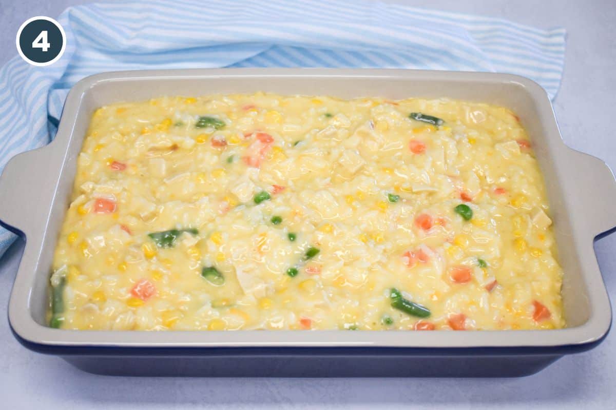 Unbaked chicken and rice casserole mixture spread evenly in a baking dish.