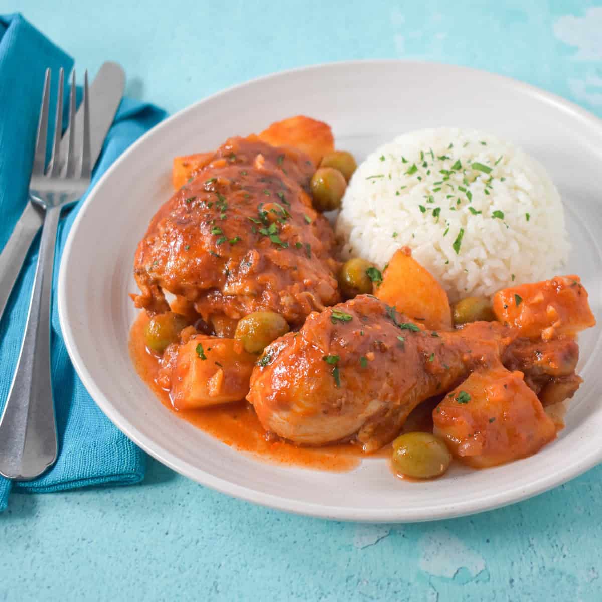 The chicken and potatoes served with white rice on a white plate.