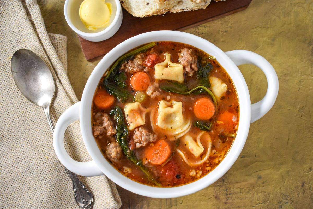 The soup served in a white bowl served with sliced bread and butter.