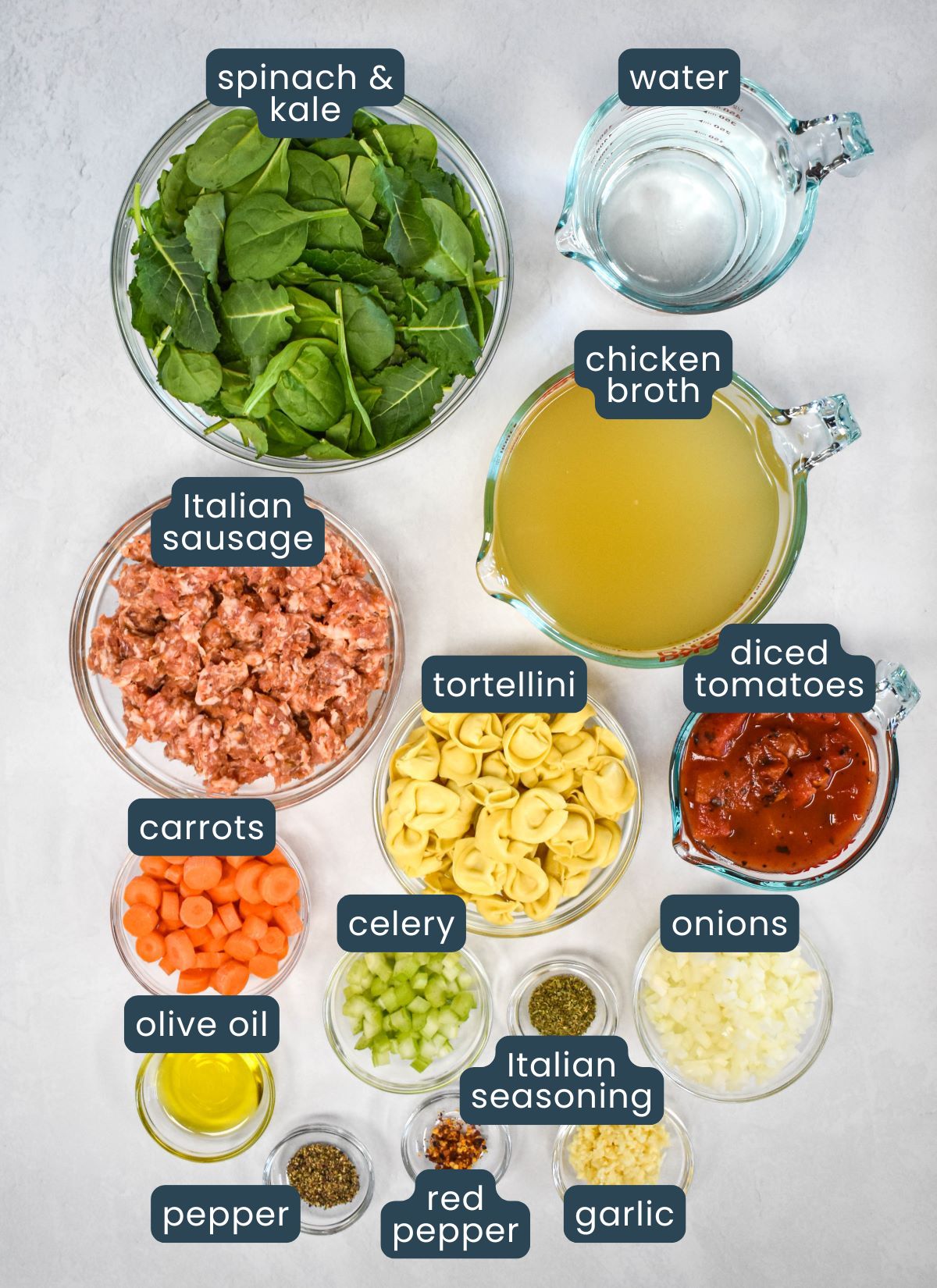 The ingredients for the soup prepped and arranged in glass bowls on a white table with each labeled.