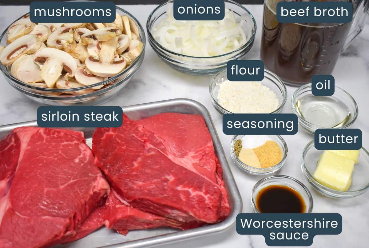 The ingredients for the recipe prepped and arranged on a white table with each labeled in blue and white letters.