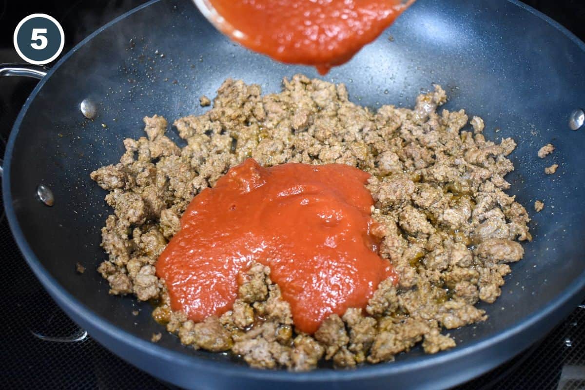 Tomato sauce being added to browned ground beef.
