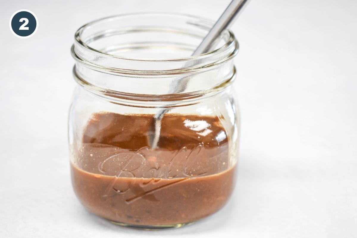 Stir fry sauce in a small canning jar with a fork for stirring.