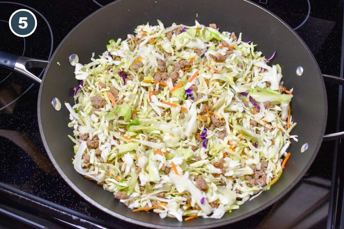 A combination of shredded cabbage and turkey in a large, black skillet.