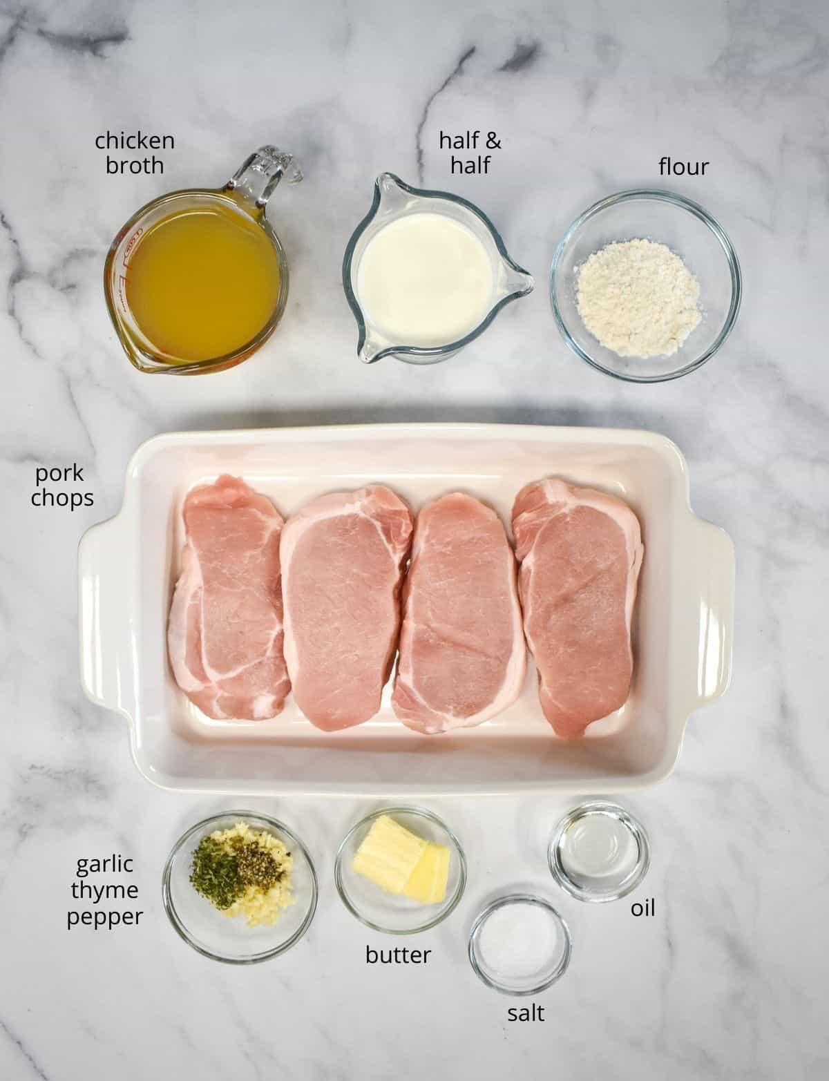 The ingredients for the creamy pork chops prepped and arranged on a white table.