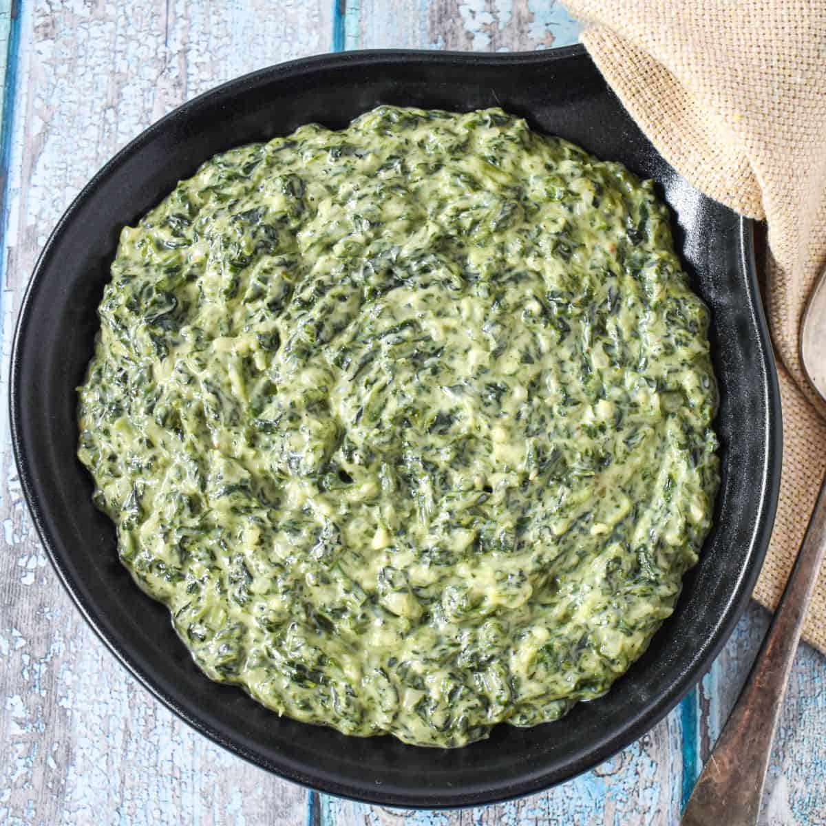 The creamed spinach served in a black skillet.