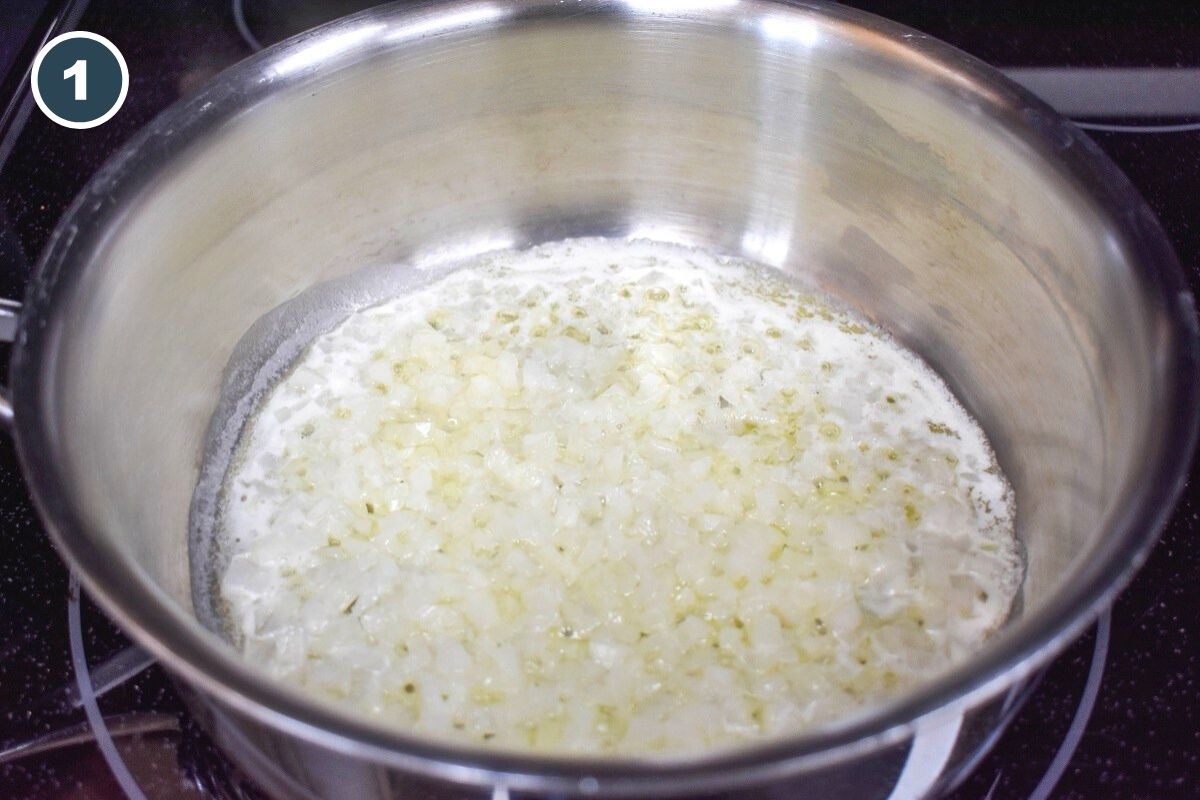 Onions cooking in butter in a stainless steel pan.