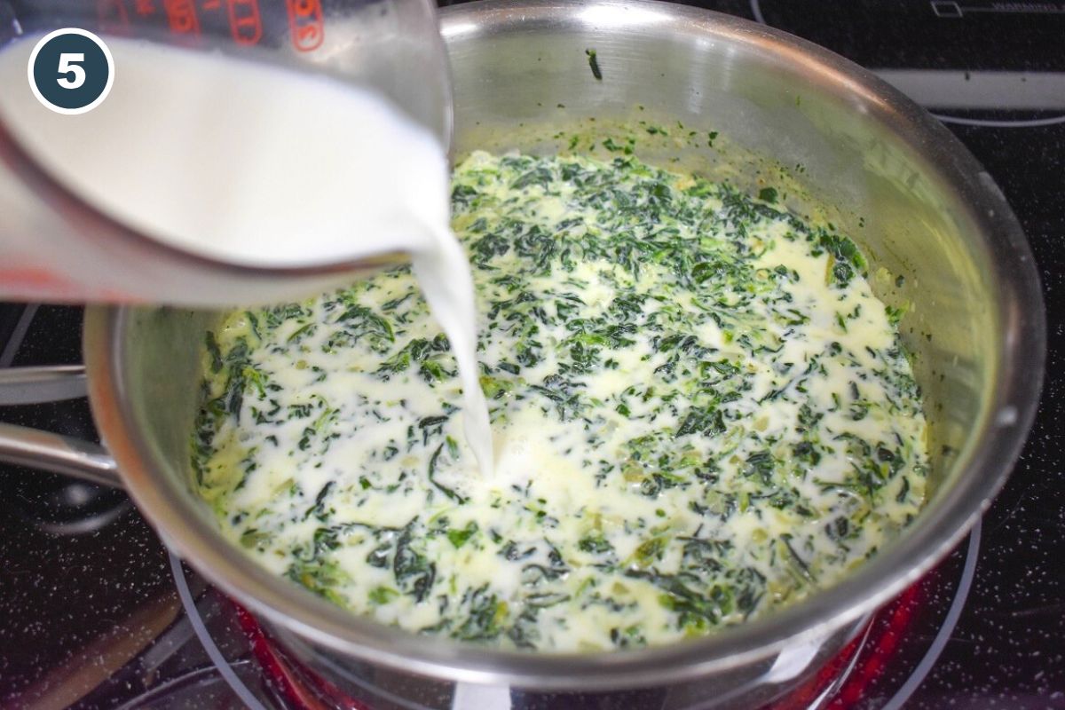 Milk being poured into the pan with the spinach mixture.