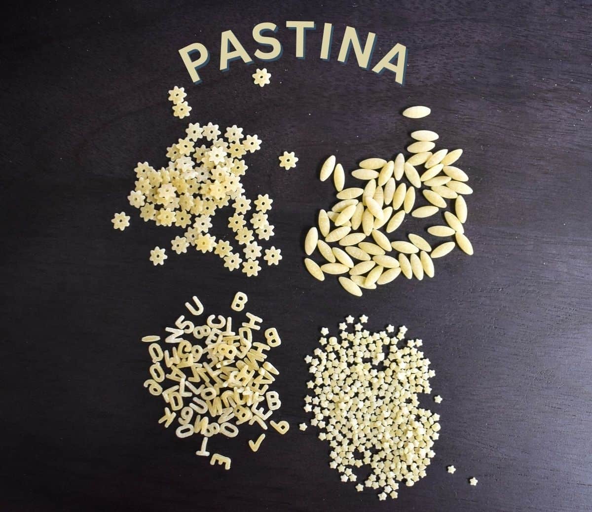 Four types of pastina laid out on a black board.