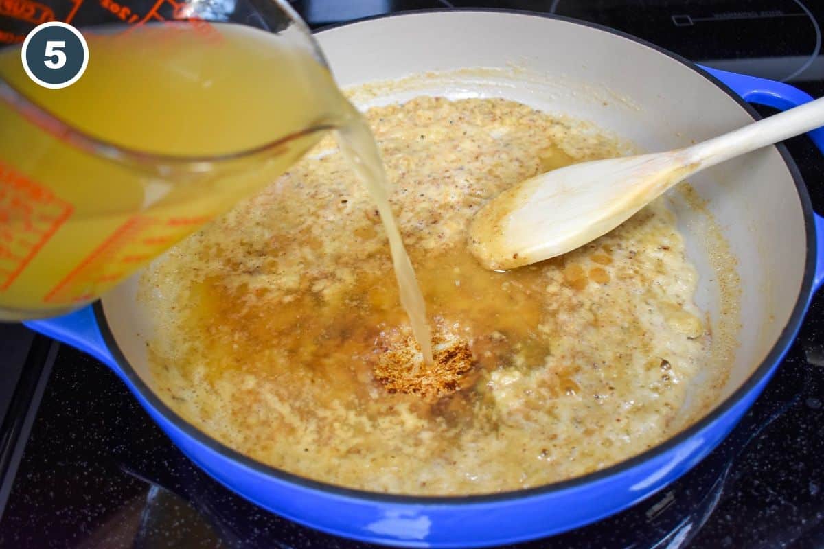 Pouring chicken broth from a measuring cup into a skillet with a mixture of butter and flour, using a wooden spoon to stir the ingredients together.