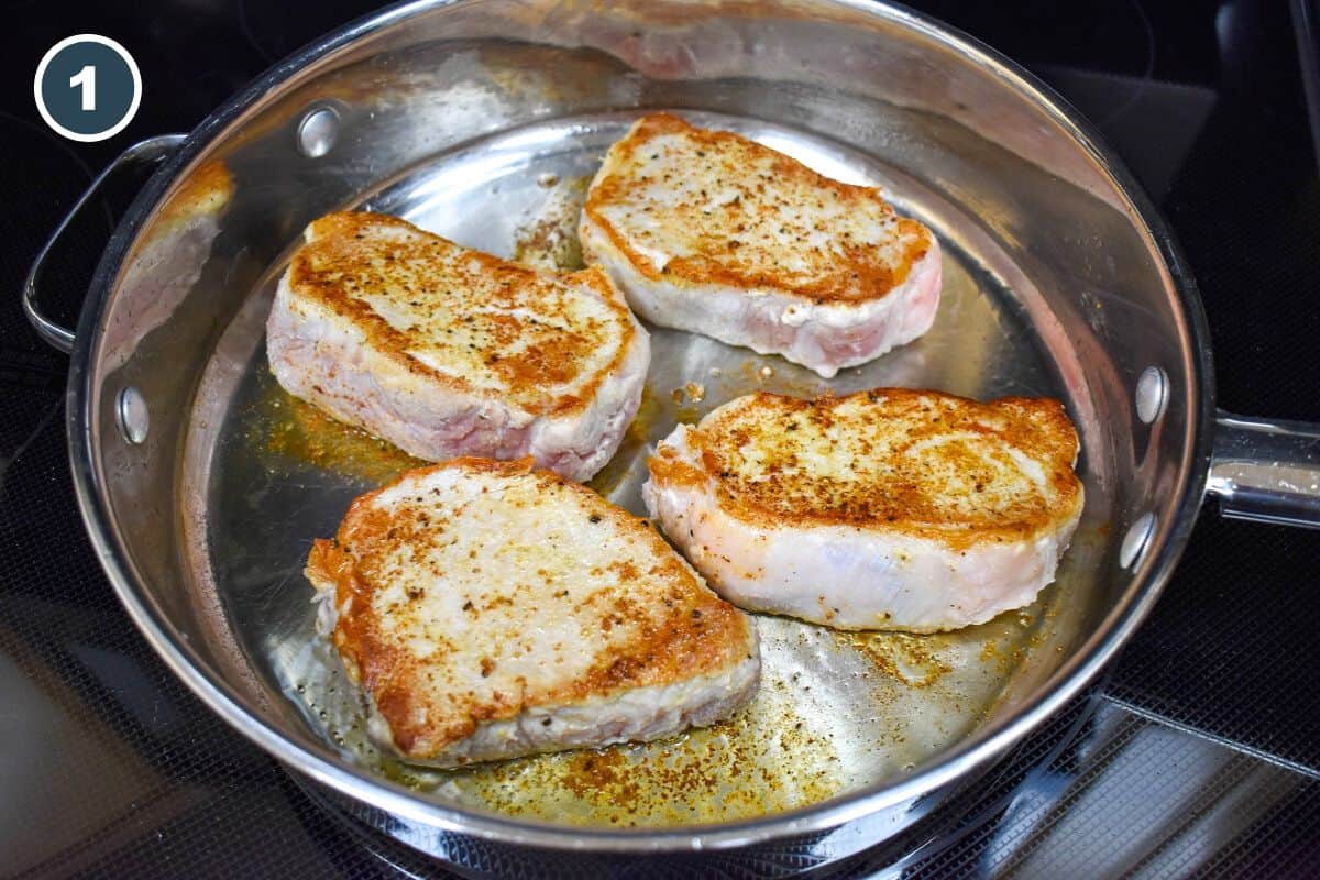 Four browned pork chops in a large skillet.