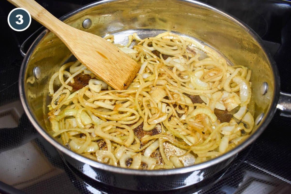 The cooked onions in the pan with a wood spatula to the side.