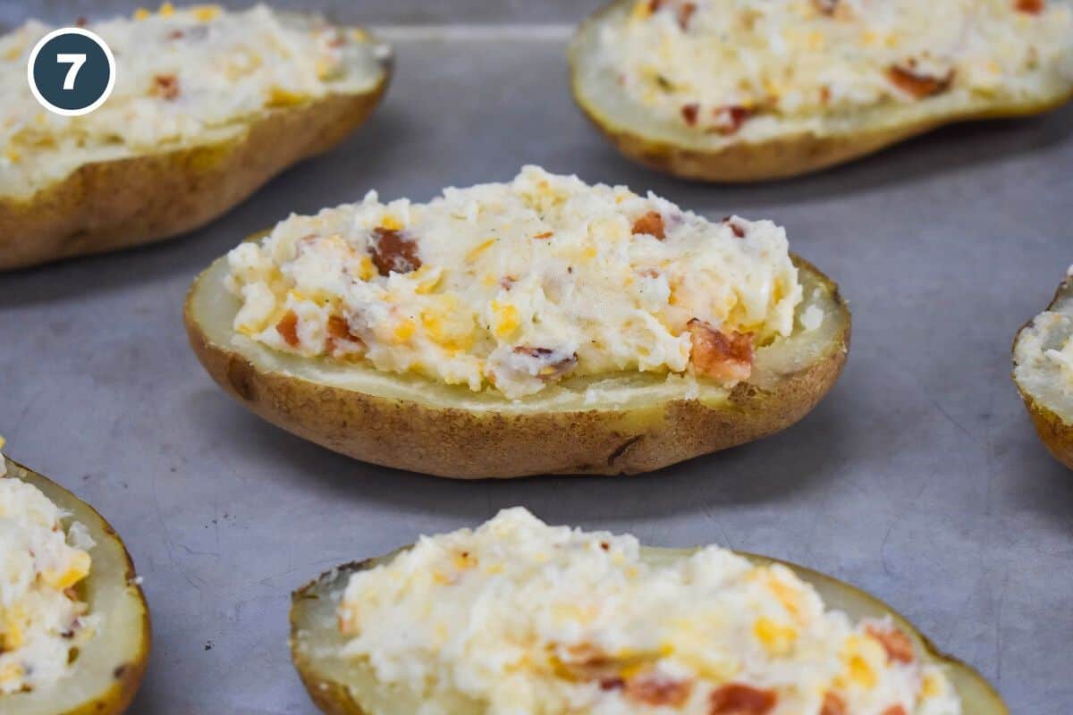 Stuffed potato halves filled with a creamy mixture of cheese and bacon are arranged on a baking sheet, ready to be baked.