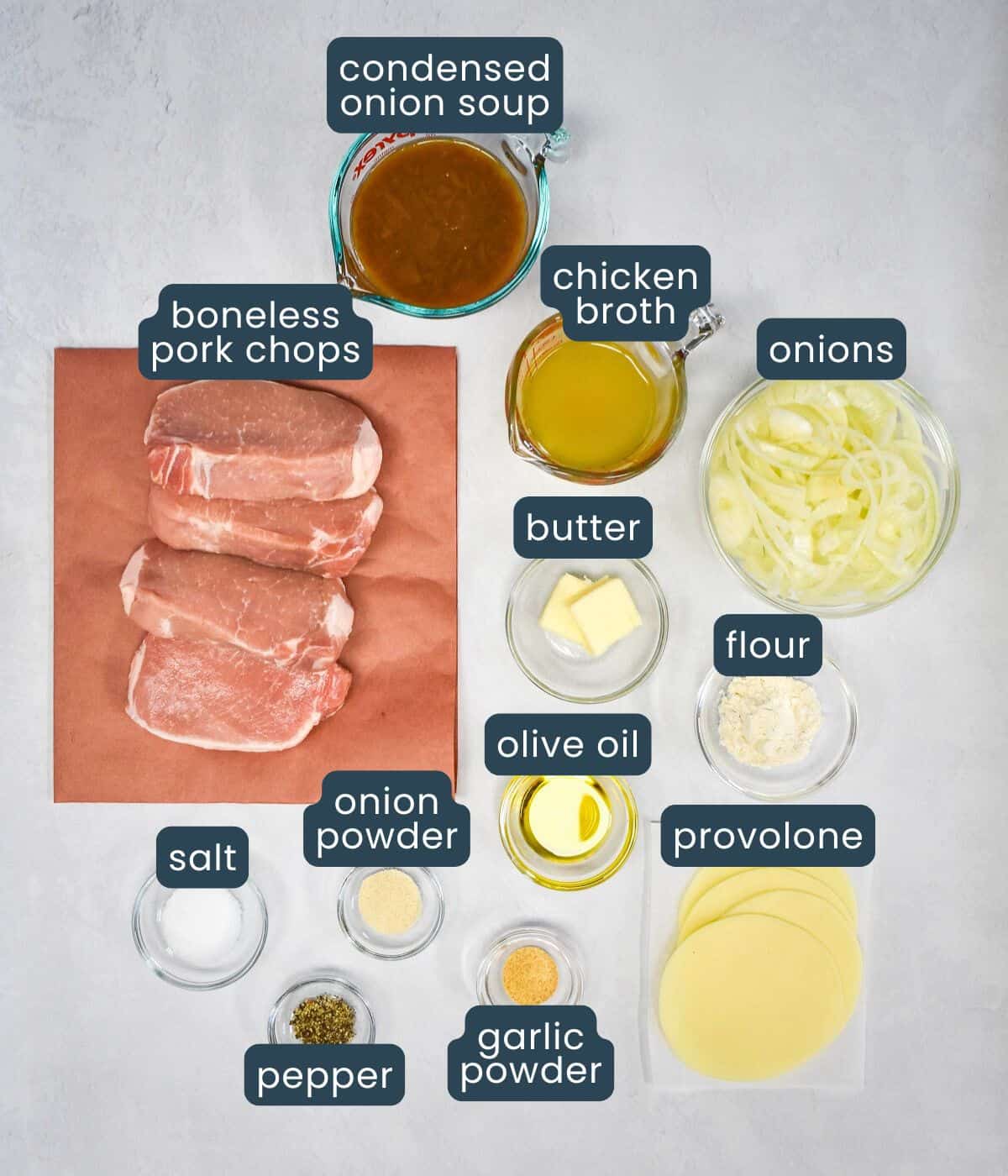 The ingredients for the dish, prepped and arranged on a white table with each labeled in blue and white letters.