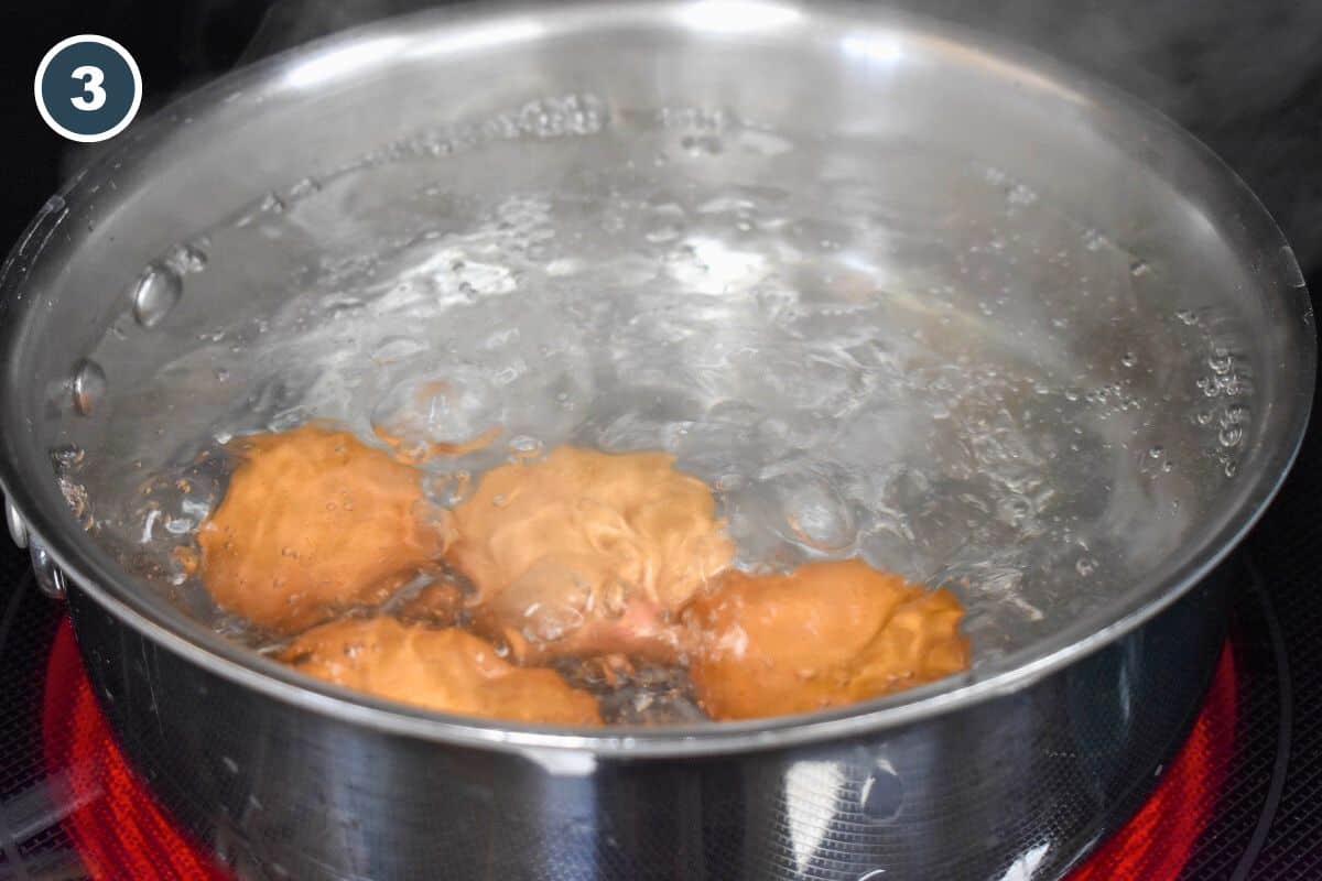 An image of four brown eggs boiling in a saucepan.