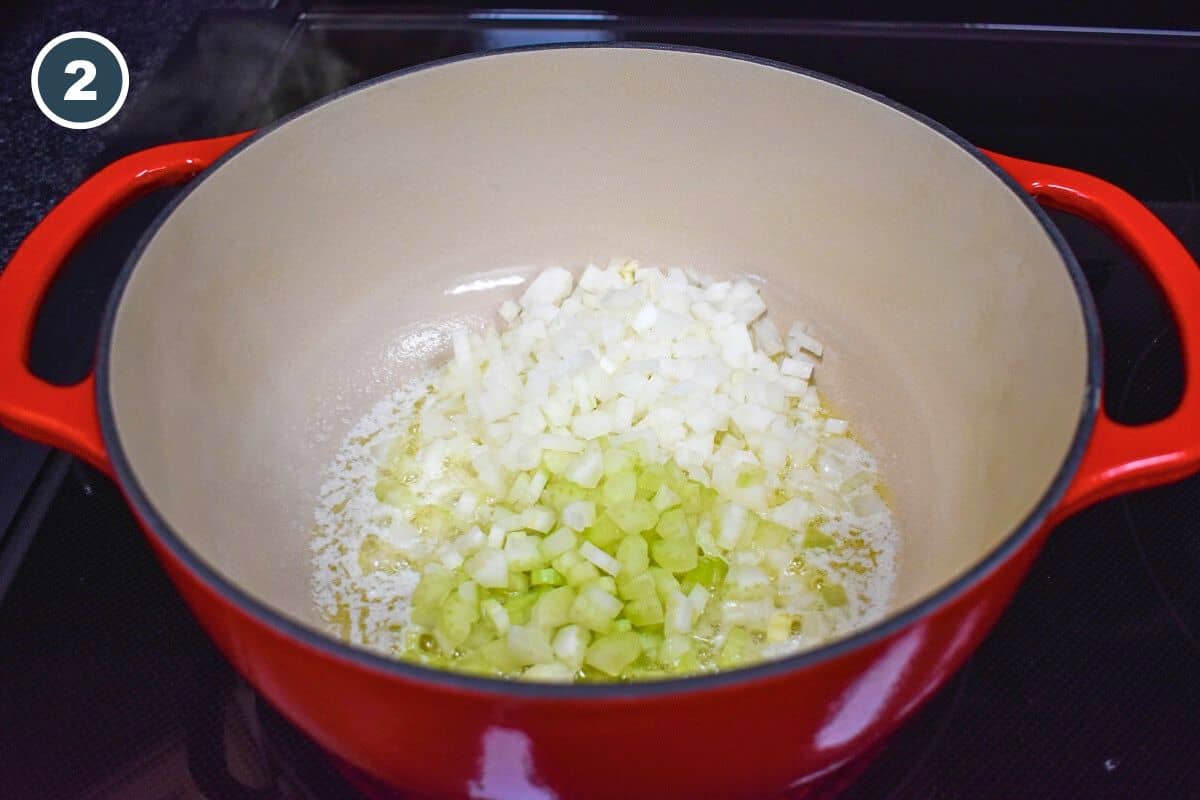 Diced onions and celery in a large, red pot.