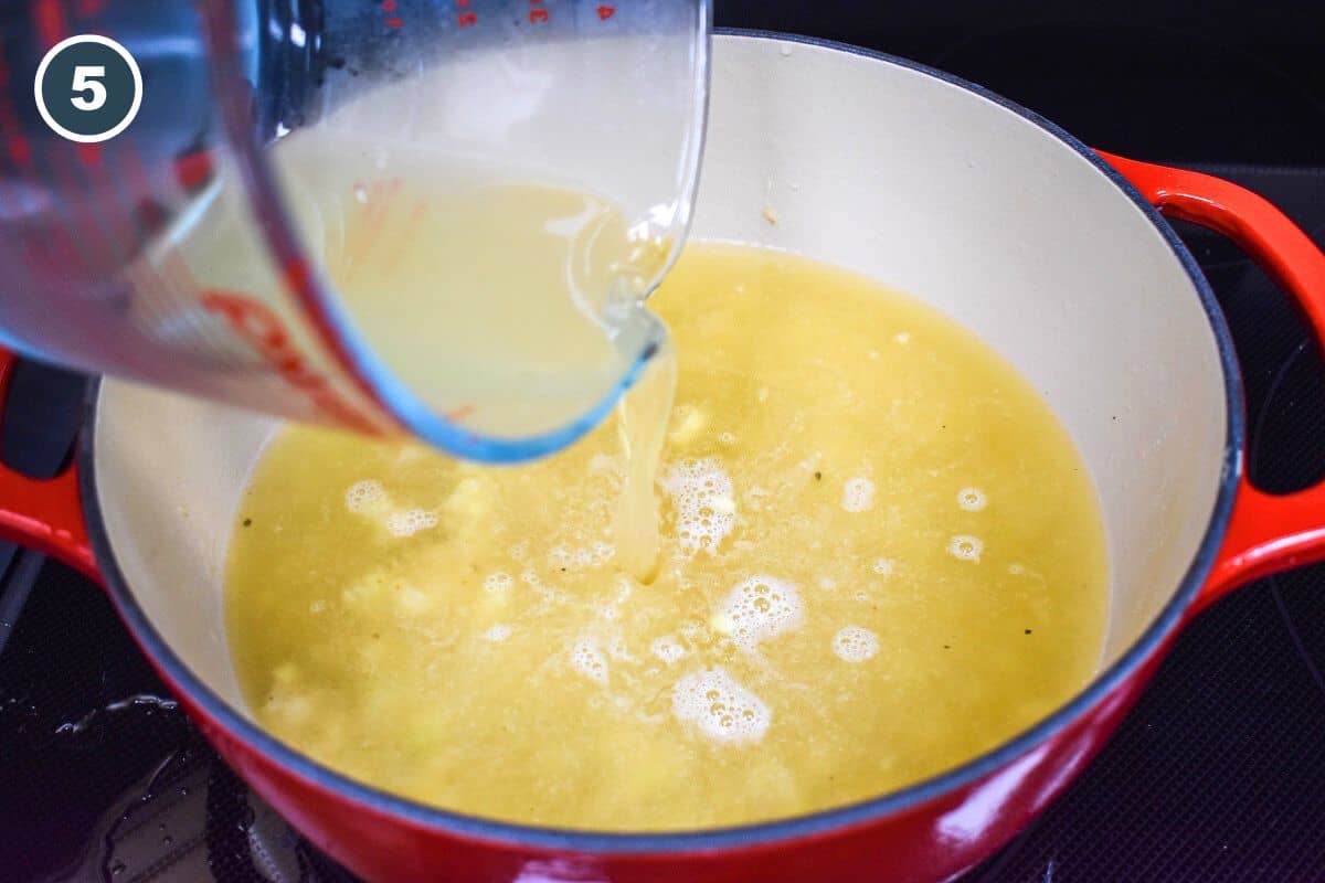 Chicken broth being added to the ingredients in the pot.