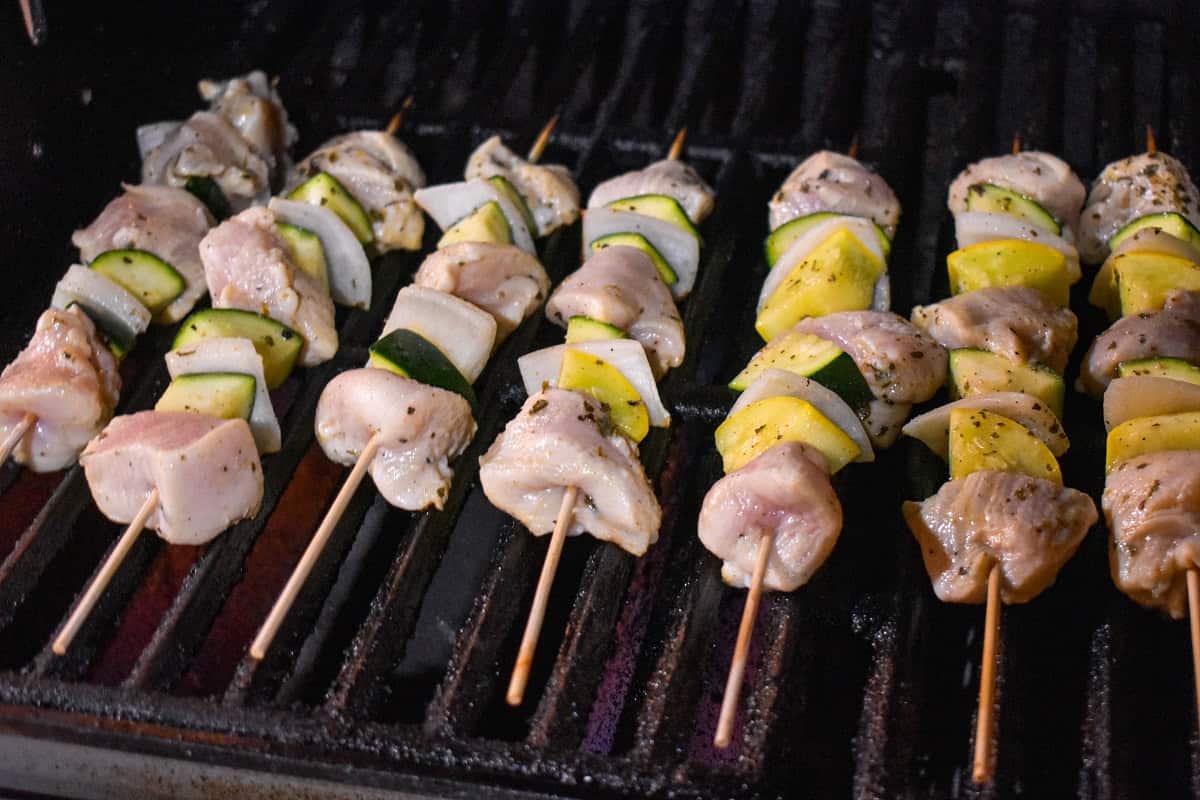 Chicken and vegetable skewers arranged on a grill.