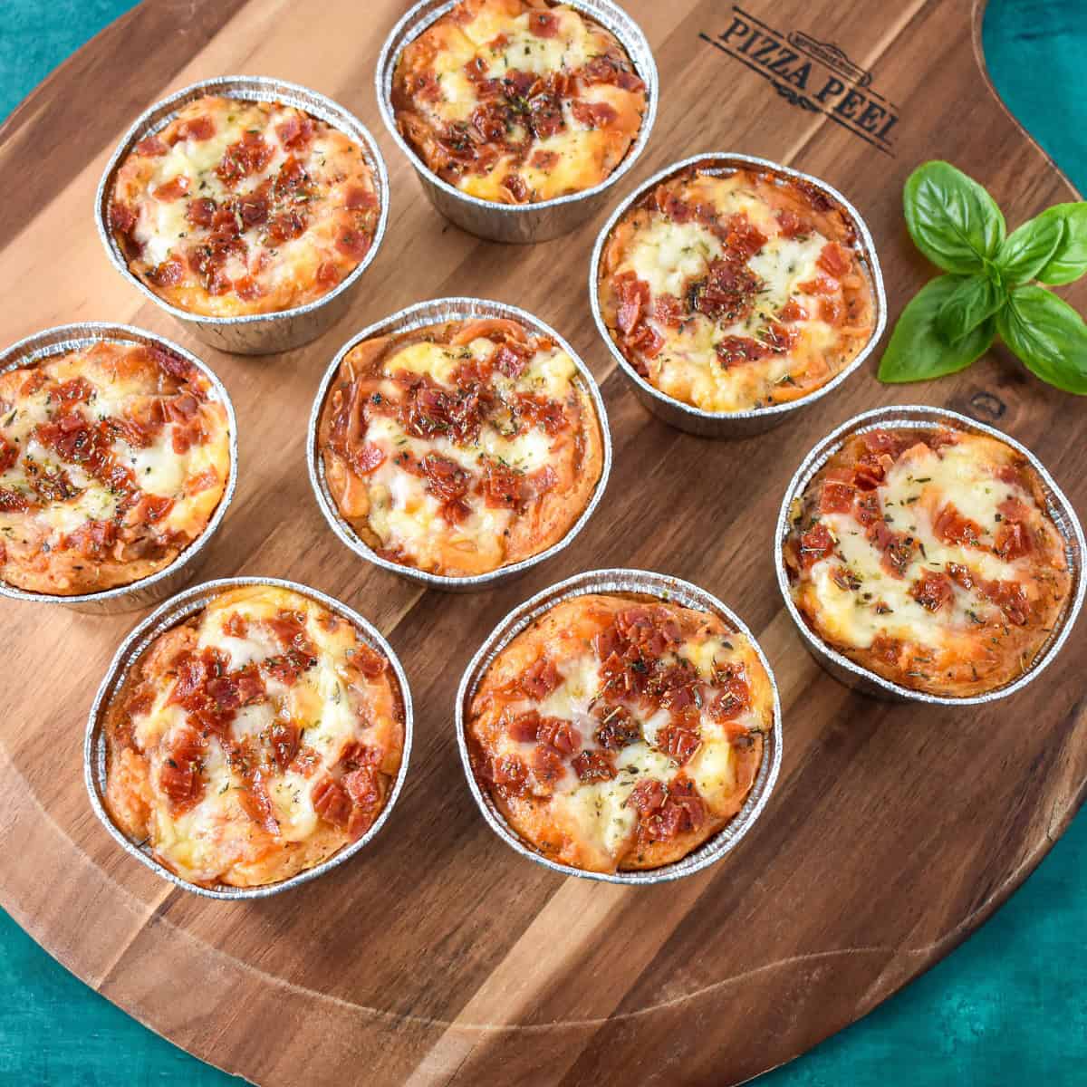 The individual pizza pot pies arranged on a wood board with a sprig of basil.