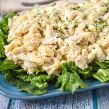Macaroni tuna salad served on a bed of lettuce on a blue platter.