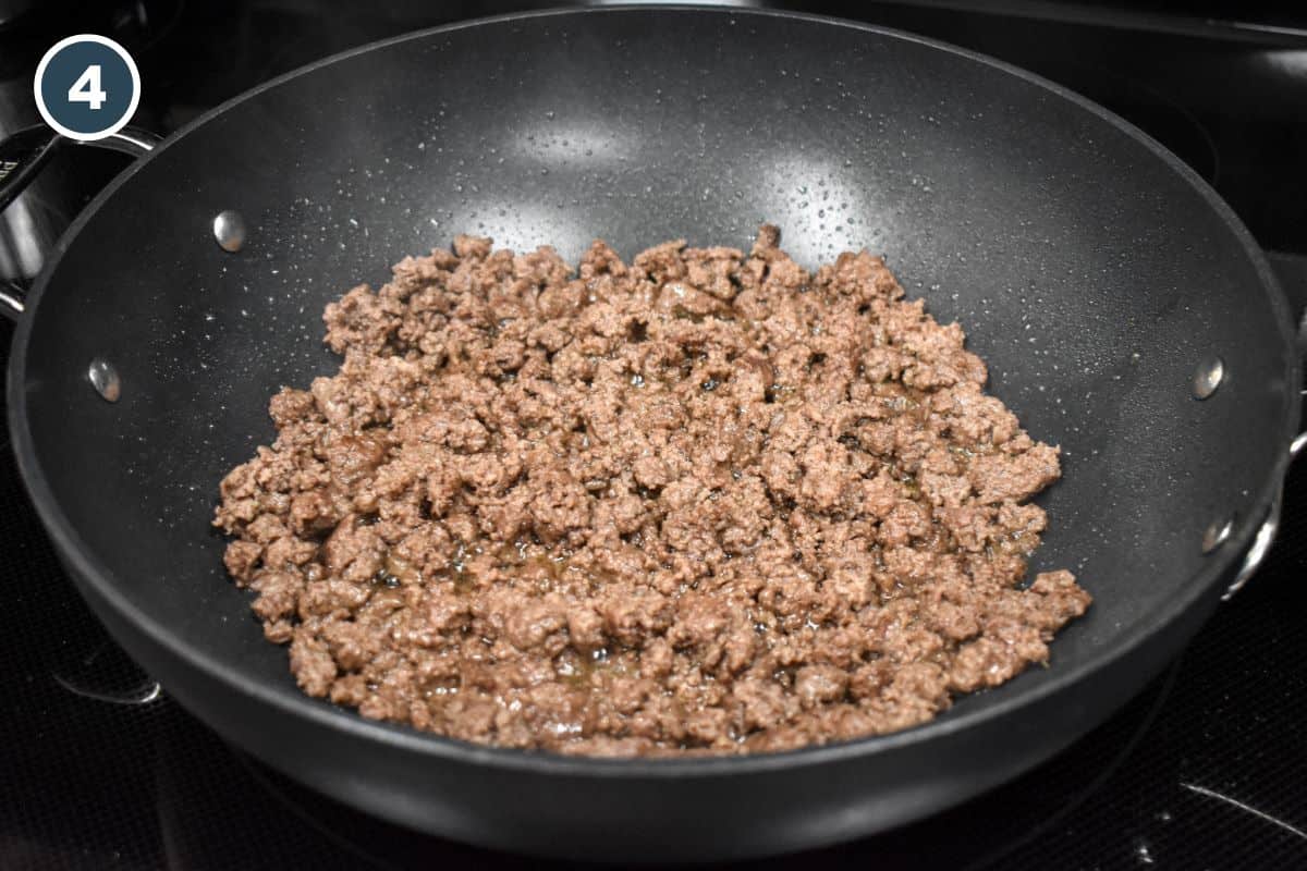 Browned ground beef in a large, black pan.