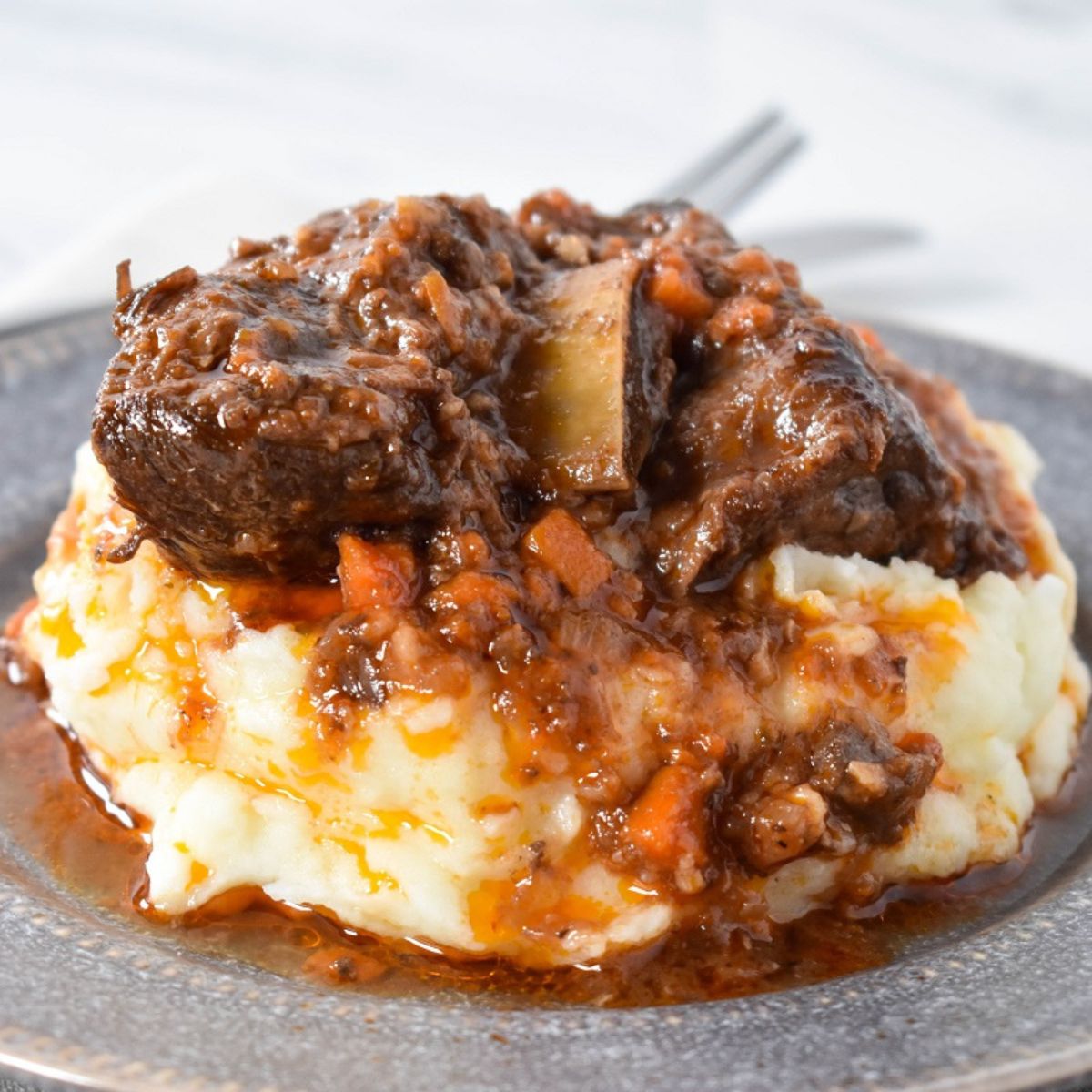 Short ribs served with the sauce on a bed of mashed potatoes.