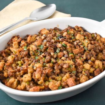 The chestnut sausage stuffing in a white casserole dish garnished with chopped parsley and sage.