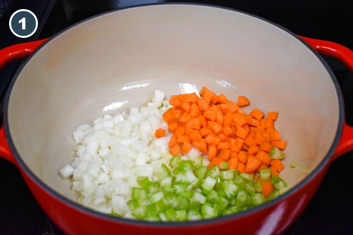 Diced onions, carrots, and celery in a red pot.