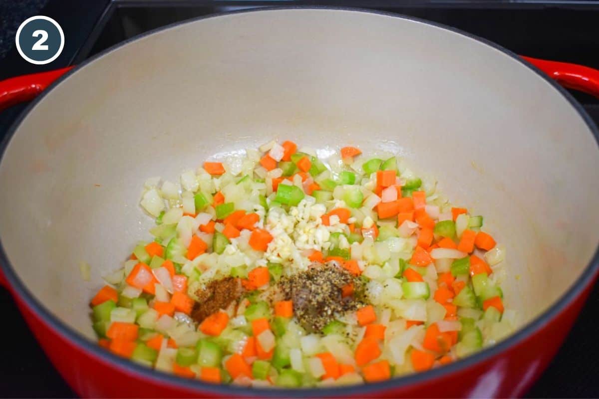 Minced garlic and spices added to the onions, carrots, and celery in the pot.