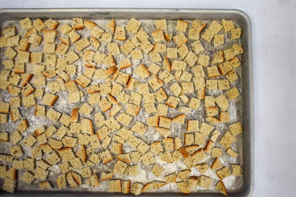 Rye bread croutons arranged on a large baking sheet.