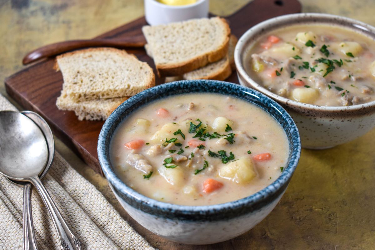 Two bowls of the finished soup, garnished with parsley and served with sliced bread.