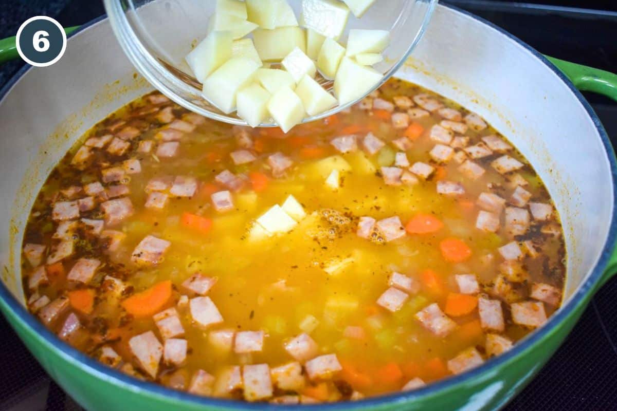 Diced potatoes being added to the rest of the ingredients in the pot.