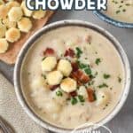 A bowl of creamy clam chowder topped with bacon, parsley, and oyster crackers, with extra crackers and bacon on a wooden board in the background. Text overlay reads "Clam Chowder" and "Easy Recipe!".